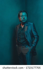 Man In Suit Stands In Corner Of Empty Room. Serious And Pensive Expression.