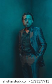 Man In Suit Stands In Corner Of Empty Room. Serious And Pensive Expression.