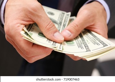 Man in suit and tie hold in arm pack of hundred dollar bills closeup. Stock market, exchange, earn pile, rich present, gift, employer prepayment, service gratitude concept