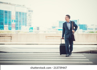 Man With A Suitcase Crossing The Road To Leave The Airport