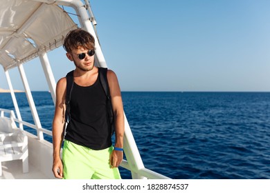  Man In Sunglasses Green Shorts And Black Tank Top On A Yacht In The Sea.