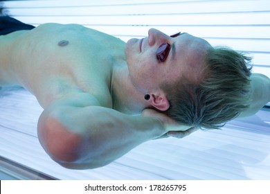 Man With Sunglasses On Tanning Bed In Solarium