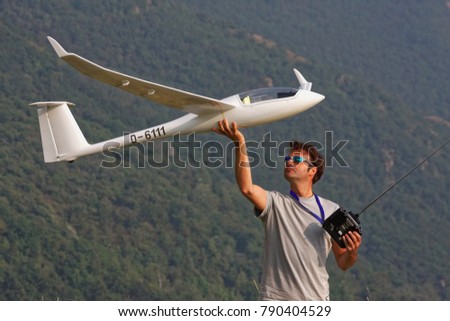 Man in sunglasses is playing with a ero plane glider discus 2c model with remote control in the top of a mountain