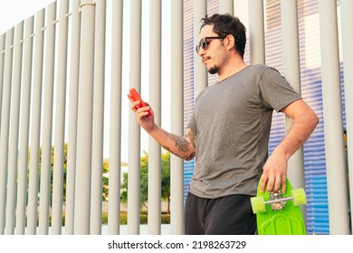 man with sunglasses and skateboard checking his cell phone in the park on a sunny day. - Powered by Shutterstock