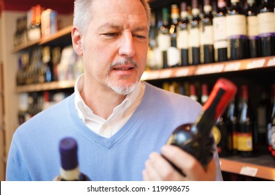 Man in a supermarket comparing two wines - Powered by Shutterstock