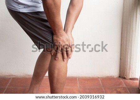 A man supporting herself from numbness, muscle weakness, pain, and tingling in the knee nerve endings. This is a side effect of Guillain-Barre Syndrome after vaccination against COVID-19.