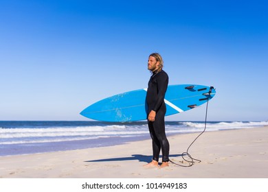 Man With Surf Board On The Ocean Shore. Surfer In A Wet Suit. Nazare, Portugal.