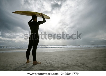 Man, surfer and wetsuit at beach for waves, sport or exercise on sandy shore in outdoor fitness. Rear view of male person or athlete with surfboard for surfing on ocean coast, sea or water in nature