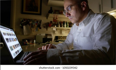Man surfing the web with laptop at home during night time.