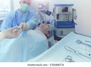 Man surgeon at work in operating room - Shutterstock ID 1703408776