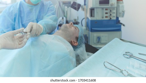 Man surgeon at work in operating room - Shutterstock ID 1703411608