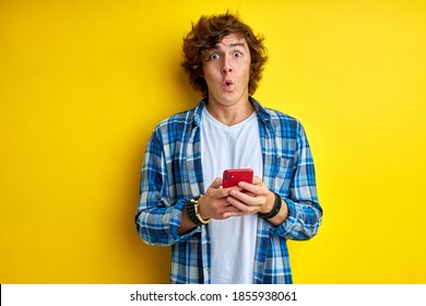 man is surprised by news on smartphone, stand emotionally reacts on someting he read, hold smartphone in hands