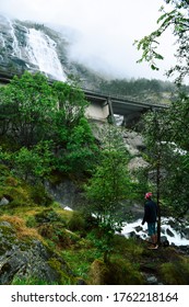 Man surrounded by trees and under a waterfall looking at the view