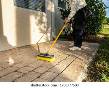 Man Sweeping Brick Paver Stone Porch With Push Broom.