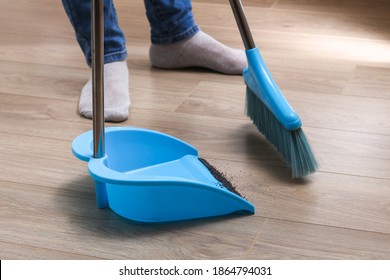 The man sweeps the debris into a blue scoop with a brush. - Powered by Shutterstock