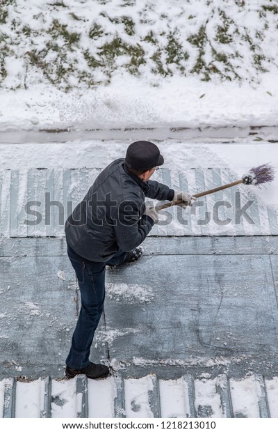 man sweeps the snow with a\
broom