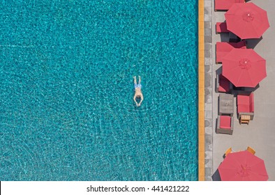 A Man Swim In The Pool At The Hotel With Red Beach Umbrella. View From Above
