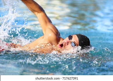 Man swimmer swimming crawl in blue ocean open water. Portrait of an athletic young male triathlete swimming crawl wearing cap and swimming goggles. Triathlete training for triathlon. - Powered by Shutterstock