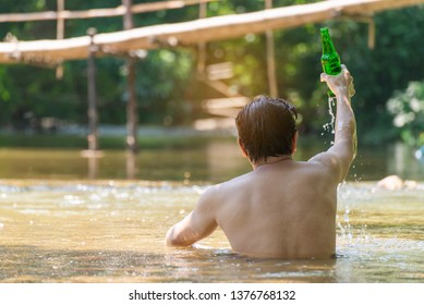 Man Swimming And Drink Alcohol , Young Man With A Bottle Of Beer Lying On Canal In The Forest,Relax At Canal And Resort. Summer Splash,