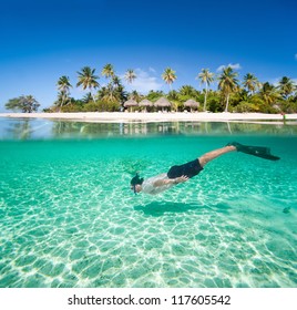 Man swimming in a tropical lagoon in front of exotic island