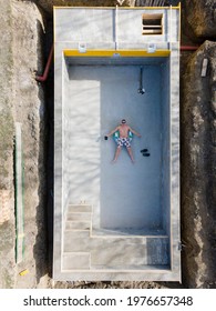 Man In Swimming Trunks Lies In Not Yet Finished Pool On A Floating Tire And Takes Selfie With Drone