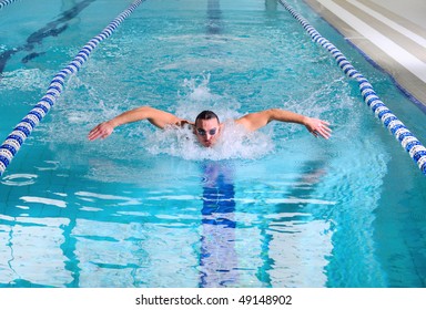 man swims using the butterfly stroke in indoor pool