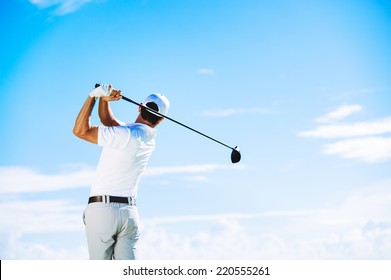 Man Swinging Golf Club With Blue Sky Background