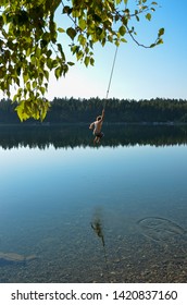 Man Swinging On A Rope Swing Into A Lake In Canada 