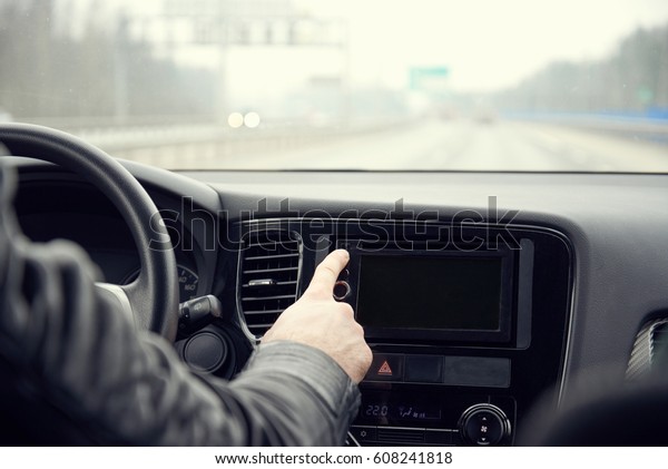 Man switching on car\
radio.