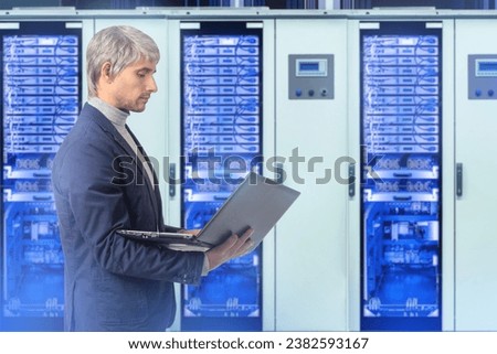 Man system administrator. Programmer with laptop. Software development for server hardware. System administrator controls servers. Man stands with computer in hands. Guy works as system administrator