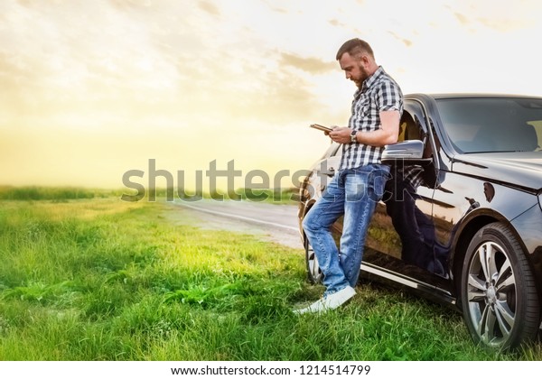 man with a tablet at\
the car on the road