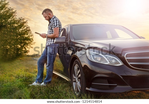 man with a tablet at\
the car on the road
