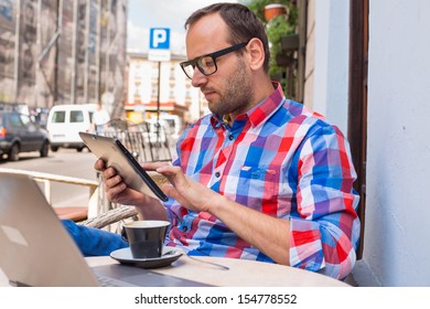 Man with tablet pc in cafe. He is drinking coffee.