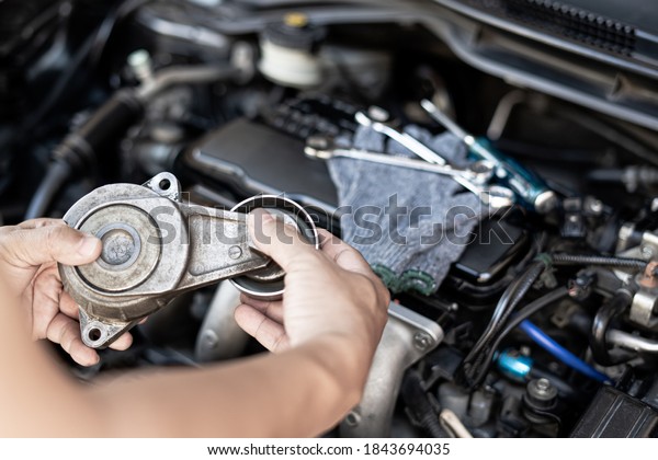 A man take off Belt Tension\
Pulley in old part car engine Replacement of spare parts in engine\
room