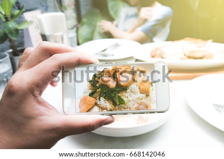 A man take a salmon cubes spicy sauce pictures from smartphone in garden restaurants