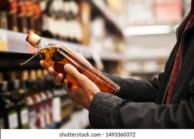 A man takes alcoholic drinks from the supermarket shelf. Shopping for alcohol in the store. 