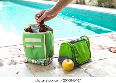 A man takes a bottle of beer from a portable refrigerator bag for food and drink. Pool party - Powered by Shutterstock