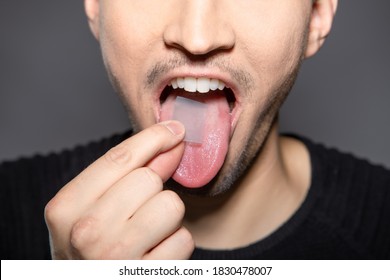 man takes breath stripes on his tounge that refreshes breath in mouth, removes smell and kills bacteria and germs