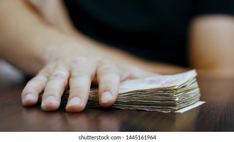 A man takes a bunch of money from the table, bribe, corruption, deal - Shutterstock ID 1445161964