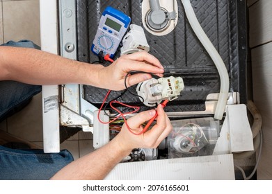 A Man Takes Measurements With An Electric Tester Of Dishwasher Parts