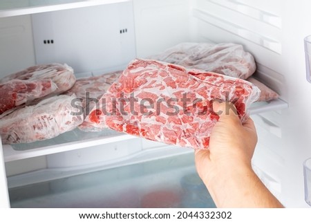 The Man takes out a bag of frozen meat from the freezer in the kitchen at home. Frozen food
