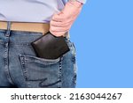 The man takes out a black purse from his back pocket, close up