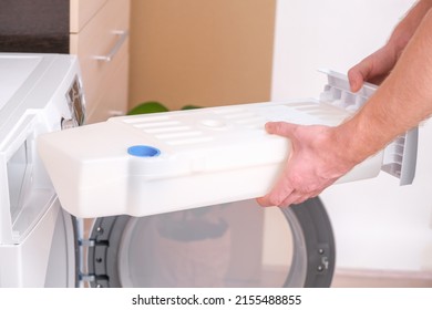 A man takes out a container from the dryer to collect water squeezed out of wet laundry.