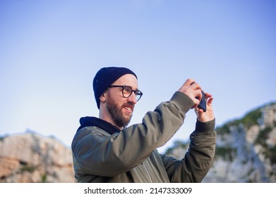 man takes photo with the phone at the edge of a cliff of the Mediterranean sea - Powered by Shutterstock