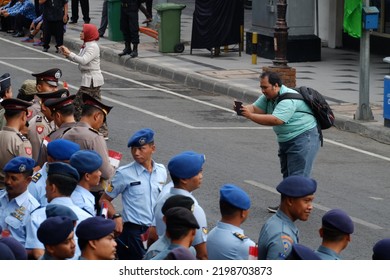 A Man Takes A Picture Of Police Officers Who Are Lined Up On The Side Of The Road Waiting For The Theatrical Event To Start Using A Smartphone (SUrabaya, 19 September 2018)