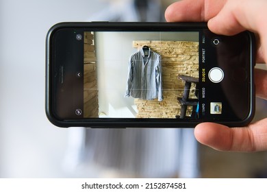 the man takes a picture of the shirt. Online sale of used clothes