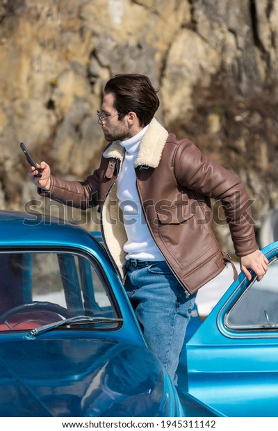 a man takes a selfie on the phone while standing near\
the car