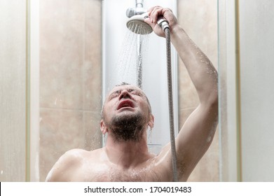 man takes a shower in the modern tiled bathroom