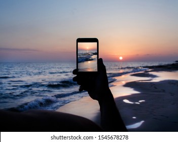 Man Takes A Sunset Photo On The Mobile Phone