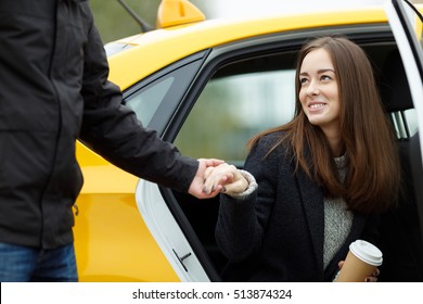 Man takes womans hand to help get out of taxi